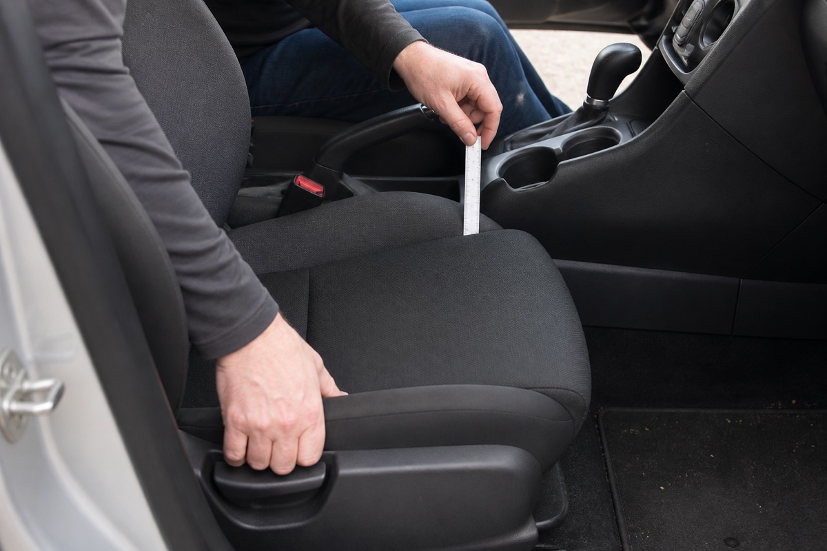 A parked-car fit check measuring the gap between a front seat and the center console before choosing a seat gap filler.