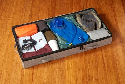 Open StorageLAB low-profile under-bed storage container filled with folded clothing and outdoor gear.