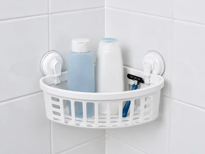 Original unbranded illustration of a white corner shower basket held to smooth gray tile by two lever suction mounts.