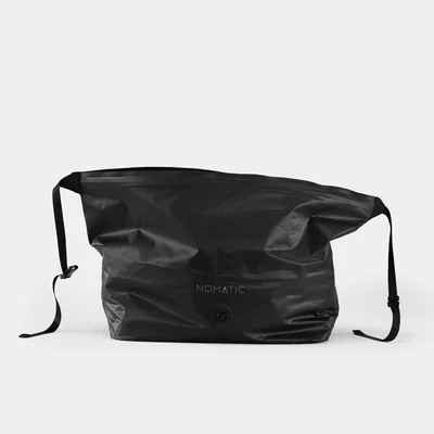 Black NOMATIC Vacuum Bag 2.0 shown compressed with its valve and adjustable straps visible.