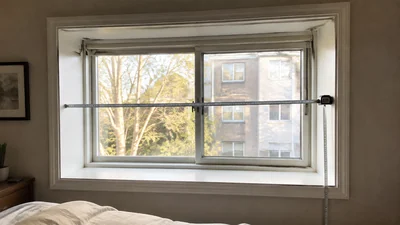 A steel tape measure spans the inside width of an ordinary apartment bedroom window, with a second tape showing the recess depth and height.
