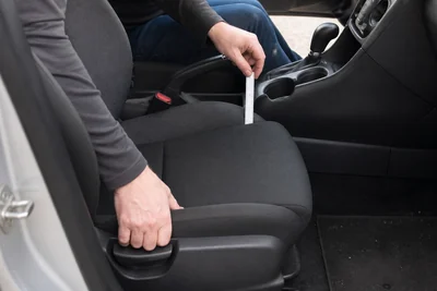 A parked-car fit check measuring the gap between a front seat and the center console before choosing a seat gap filler.