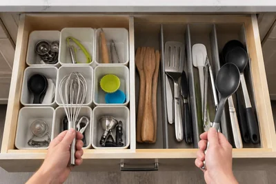 Open kitchen drawer comparing small removable bins with adjustable divider zones.
