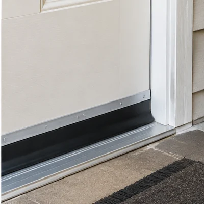 Original unbranded illustration of a slim aluminum-and-black-rubber screw-on sweep installed on a white exterior door.