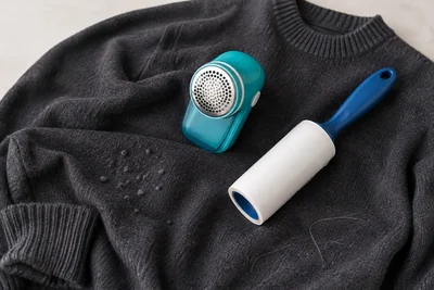 AI illustration of a fabric shaver and adhesive lint roller on a charcoal knit sweater.